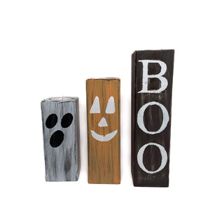 Handgjort Halloween-set i trä med tre rustika ljushållare målade som spöke, pumpa och texten BOO, fotograferade mot vit bakgrund.