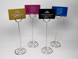 Graverade metallkort från Norrgården placerade i hållare – perfekta som visitkort eller bordsnummer med QR-kod.