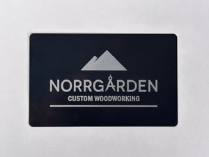 Svart graverat metallkort med Norrgårdens logotyp – stilrent och professionellt.