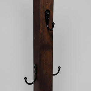 Närbild på handgjord mugghållare i trä med svarta metallkrokar