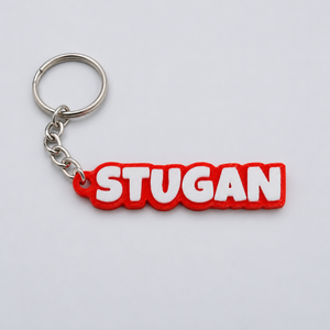 3D-printad nyckelring i TPU med texten STUGAN, vit text på röd bottenplatta
