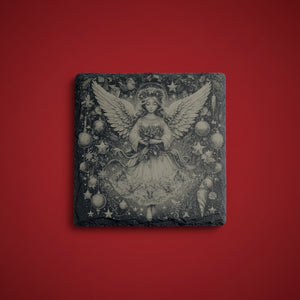 Ängel med julkulor och stjärnor graverad på skifferunderlägg.