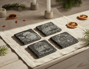 Skifferunderlägg med klassiska julmotiv, inklusive tomtar, snöglober, änglar och vinterlandskap, graverade i skiffer. Julkollektion från Norrgården.