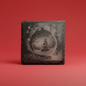 Snöglob med gran graverad på skifferunderlägg med Merry Christmas-text.