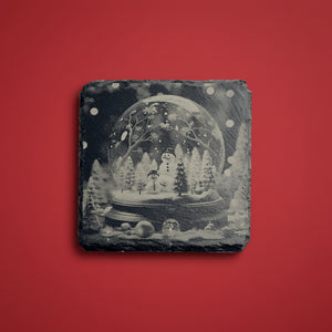 Snöglob med snögubbar och vintermotiv graverad på skifferunderlägg.