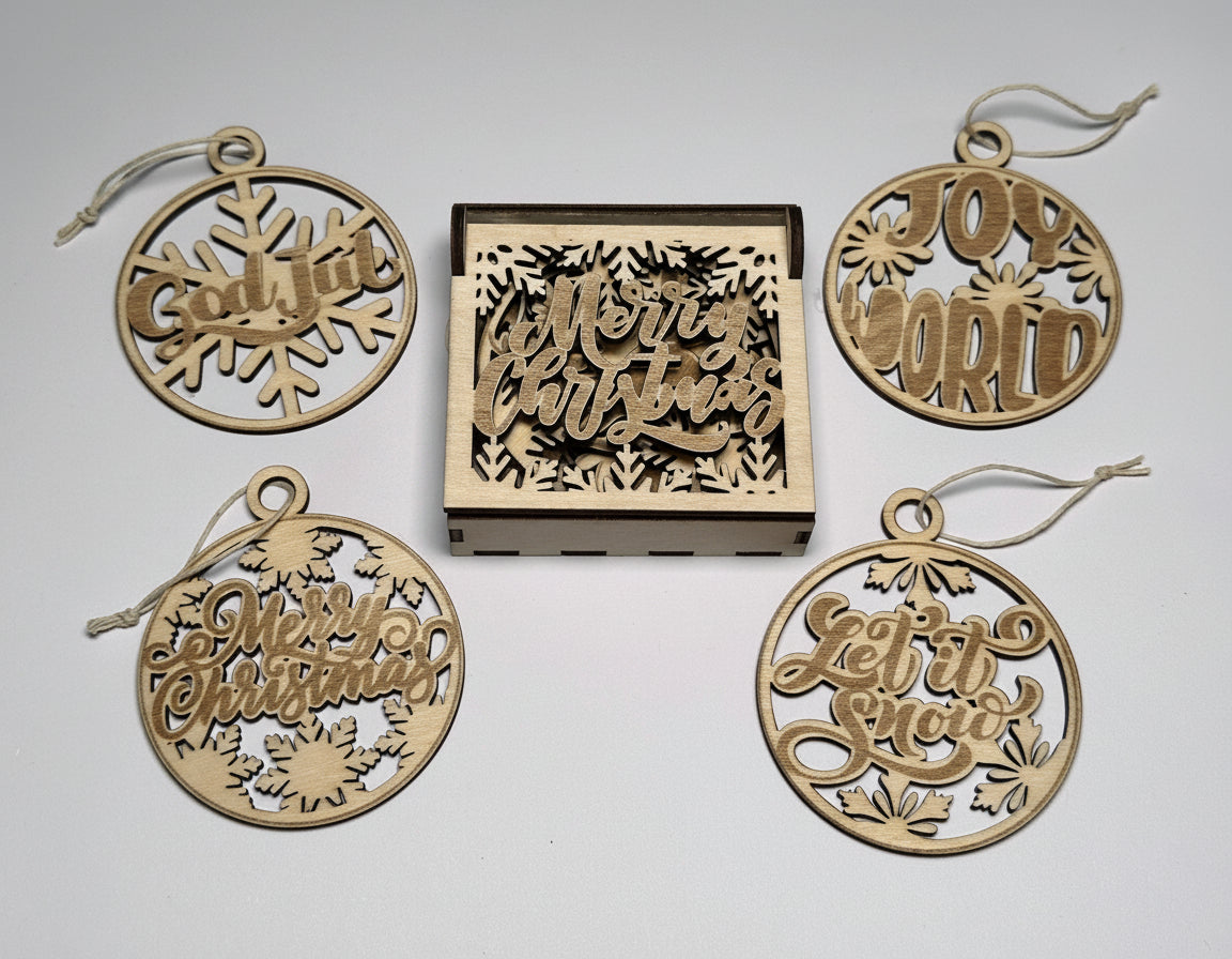 Julhängen i trä med textmotiv – Merry Christmas, Let it snow, Joy to the world och Believe. Levereras i dekorativ träask.