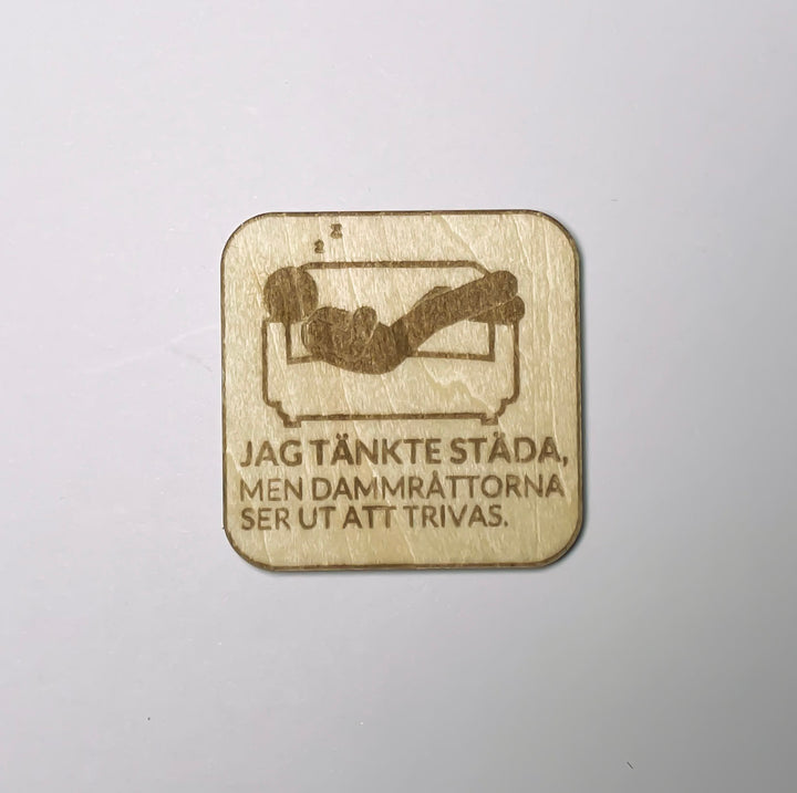 Kylskåpsmagnet i trä med texten Jag tänkte städa men dammråttorna ser ut att trivas
