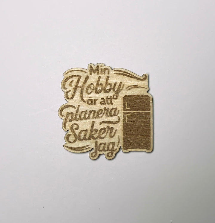 Kylskåpsmagnet i trä med kylskåpsmotiv och texten Min hobby är att planera saker