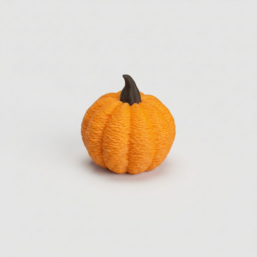Närbild på en liten orange pumpa på ca 3 cm med texturerad yta, tydliga klyftor och böjd brun stjälk