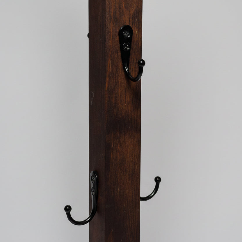 Närbild på handgjord mugghållare i trä med svarta metallkrokar