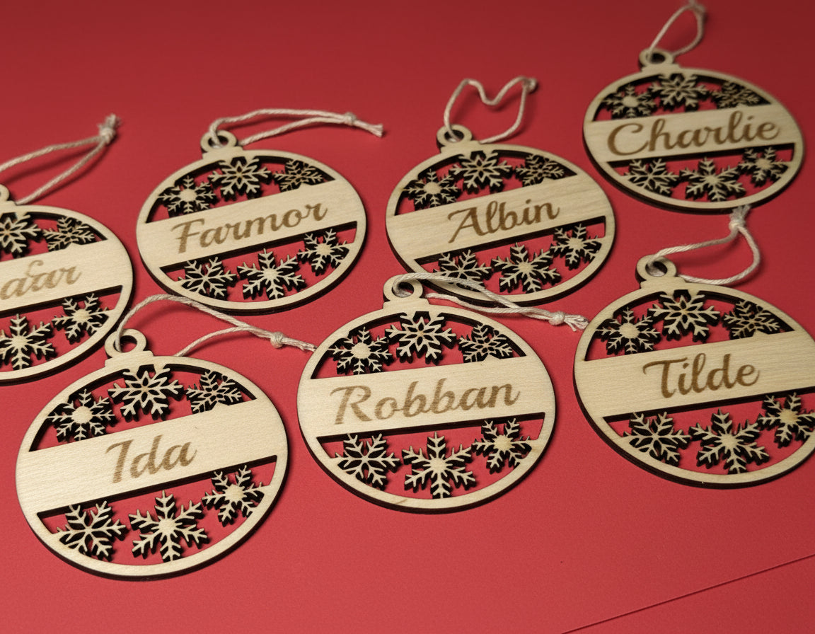 Personliga julhängen i trä med graverade namn som Farmor, Albin och Tilde, levererade i utskuren träask med texten Merry Christmas.
